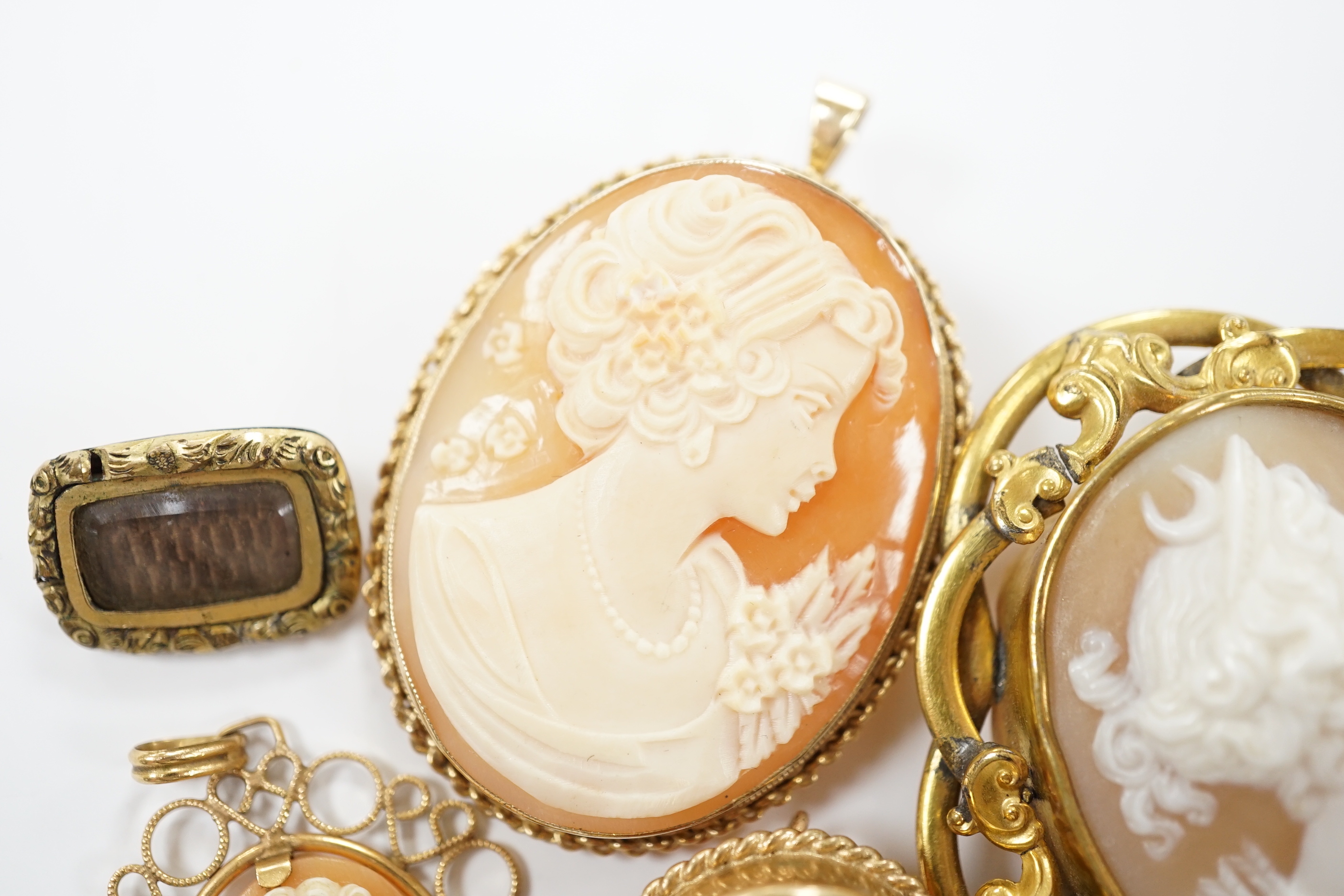 Two modern 9ct gold mounted oval cameo shell pendant brooches, largest 42cm and two other mounted oval cameo shell pendant or brooches and a mourning brooch (a,f,).